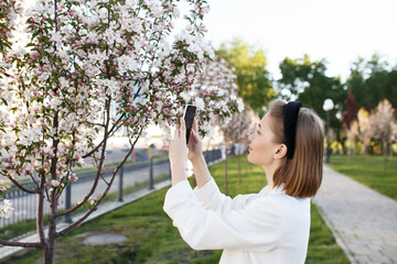 Fototapeta premium Cute girl photographer tourist blogger lady taking photos of nature on her phone outdoors, selective focus