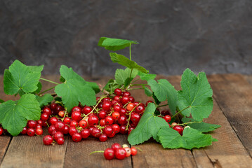 Ripe red currants with leaves, wooden table