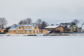 Fototapeta na wymiar Iced city lake and waterfront of old town. Winter snowy season in Haapsalu. Estonia.