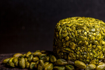 Goat cheese balls wrapped with pistachio. Cheese on black background. Traditional dinner.
