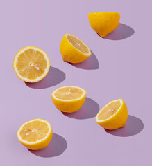Creative sunlit isometric concept with cut lemon halves arranged on abstract lilac background