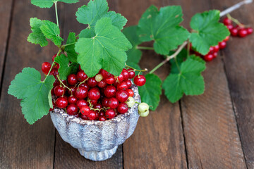 Ripe red currants with leaves, wooden table