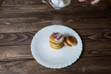 Cottage cheese pancakes or syrniki with redcurrant, icing sugar.