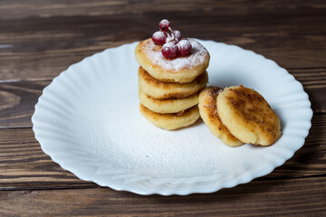 Cottage cheese pancakes or syrniki with redcurrant, icing sugar.