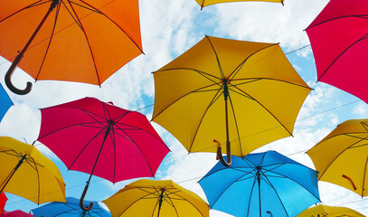 Colorful umbrellas hanging overhead over a blue sky