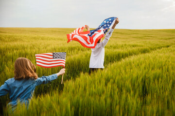 Guy and girl running in a field with an American flag in their hands