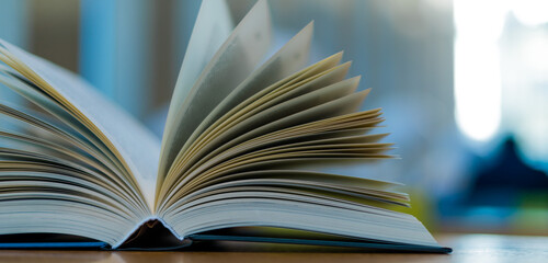 Fototapeta premium Open book lying on the table in the library