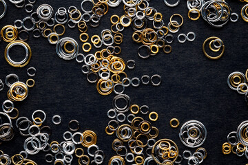 round metal links, accessories for jewelry making, scattered on a black background