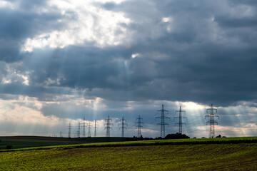 Pylons With High Voltage Energy Wires In Farmland At Stormy Weather 