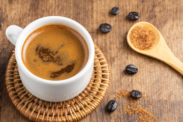 Aerial view of coffee cup, wooden spoon with brown sugar and coffee beans on wooden table, horizontal