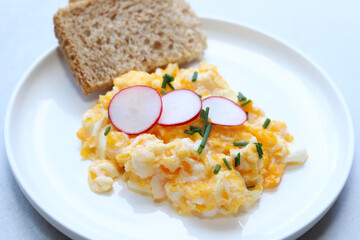 Scrambled eggs on a white plate. Healthy food or breakfast concept.