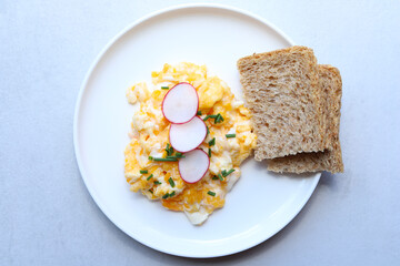 Scrambled eggs on a white plate. Healthy food or breakfast concept.