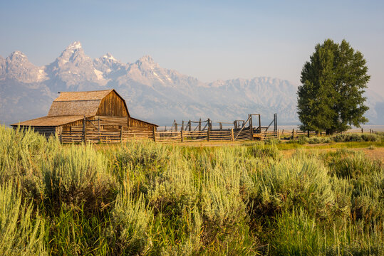 Grand Teton mountain range behind a rustic wooden barn along the famous & historic Mormon Row in Grand Teton National Park, Wyoming, United States of America