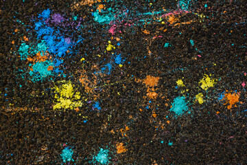 Colorful abstract background. Spots of colored chalk on the dark asphalt. Copy space.