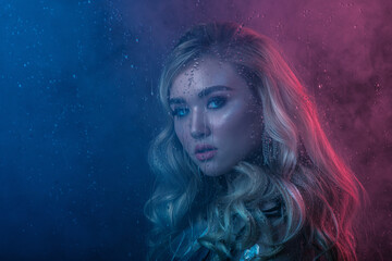 Fashion, beauty portrait of elegant blonde woman posing in colorful bright neon uv blue and red...