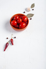 Salted red tomatoes with ingredients on a white table