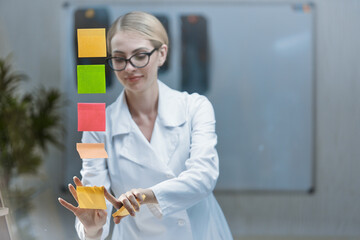 A young doctor in an office with a stethoscope around his neck and a white coat, brainstorming to...