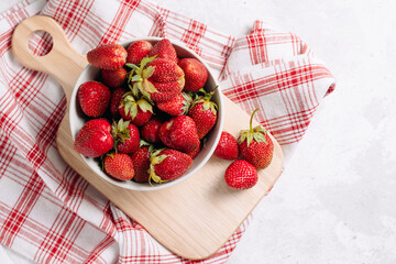 Closeup fresh garden strawberry in a plate on a wooden kitchen board with a beautiful napkin and serving, wholesome food and vitamins, diet. Top view