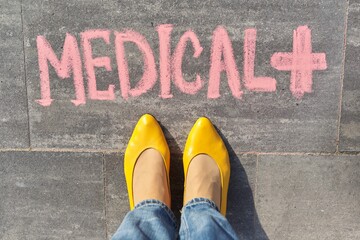 Medical concept, top view on woman legs and text written in chalk on gray sidewalk