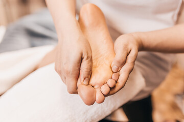 Hands of a massage therapist knead the muscles of the feet - female foot massage