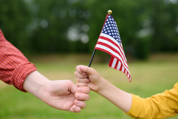 Young woman and little child holding american flag on grey background. Independence Day concept. National holiday.