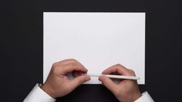 top view of a blank sheet of paper and a businessman's hands on a black table, white shirt and wrist watch