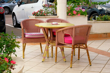Fototapeta na wymiar Empty patio in summer in recreation. Pink table and armchairs on outdoor terrace of summer cafe.