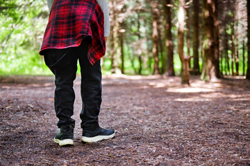 young man walking in the park. Close up view on man's legs in jeans and black leather boots with sunlight against nature blur background. - Powered by Adobe