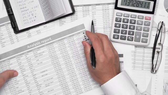 Top view of businessman working with financial statements. Modern black office desk with notebook, calc, pen and a lot of things. Flat lay table layout.
