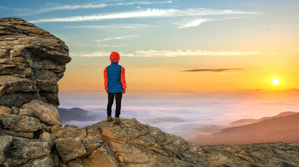 Obraz premium Young child boy hiker standing in mountains enjoying view of amazing mountain landscape at sunrise.