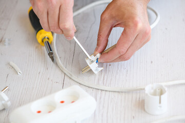 Electrician repair man hands spin and tighten screws with screwdriver at small plastic european...