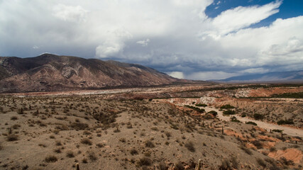 Desert landscape. Aerial view of Los Cardones National Park, in Salta, Argentina. The dry desert sand texture, canyon, and a colorful hill in the background, under a beautiful sky. 