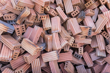 A lot of red bricks are stacked on the floor. Piles of red construction bricks scattered on the ground.