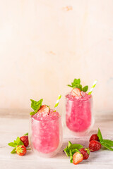 Fresh strawberry cocktail. Fresh summer cocktail with strawberry and ice cubes. Glass of strawberry soda drink on light pink background