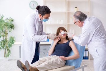 Obraz premium Two male doctors and young woman in plastic surgery concept