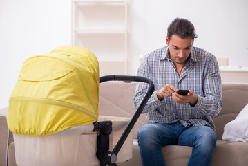 Young father looking after newborn baby at home