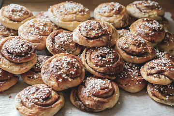 Obraz na płótnie Canvas Batch of freshly baked homemade Swedish style cinnamon rolls / buns with pearl sugar. Slightly increased contrast, vintage style photo -Image