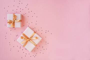 Two gift boxes with ribbon and bow on pink background with stars confetti . Top view and space for text.	