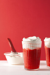 Strawberry smoothie shakes in glass with whipping cream on red background with copy space.Summer refreshing drink mocktail