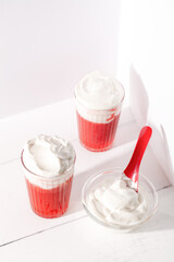Two glasses with strawberry smoothie shakes and whipping cream on white background top view.Summer refreshing drink mocktail