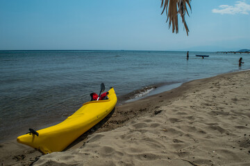 Yellow racing canoe holding still at the shore of a beach in Greece