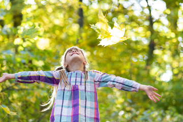 Portrait of happy pretty child girl having fun in autumn forest. Positive female kid enjoying warm day in fall park.