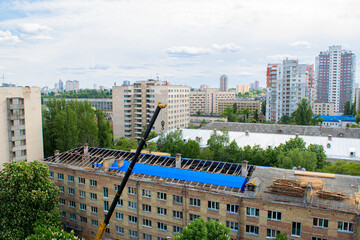 Workers repair and replace roofing on an old red brick building. Spring construction work. Repair and maintenance of city buildings in proper form. © jana_janina