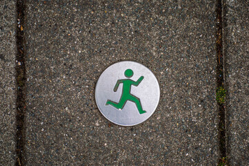 Jogging route sign on a grey concrete pavement tile - Powered by Adobe