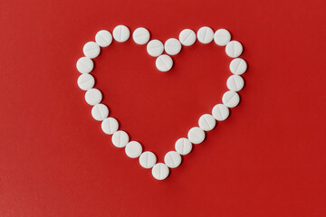 Top view of heart made of white pills over red background. Heart and cardiovascular disease, health and treatment concept