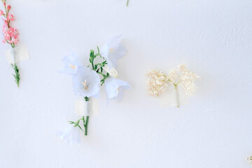 A lot of flowers of different colors fixed on a wall of white, blue, pink, yellow colors. Wall Flower. Decoration of the walls. Selective focus.