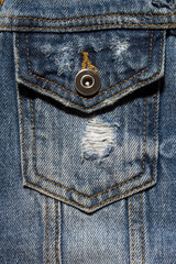 Vintage denim texture background: jacket close-up. Blue torn denim pocket. Stylish torn denim background. Closeup pocket on blue denim jean and button. Denim, fashionable jacket.