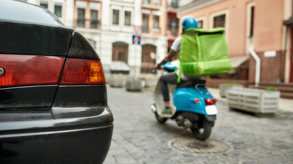 Naklejka premium Serving you is my work. Delivery man in helmet with thermo bag or backpack riding a motor scooter along the city, delivering food. Courier, delivery service concept