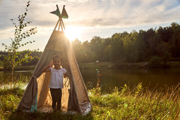 Girl at sunset in nature. Wigwam by the lake. New home in a hut. CHILDREN'S GAMES. High quality...