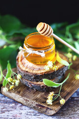 Selective focus. Linden honey in a jar. Leaves and flowers of linden. Freshly linden honey.